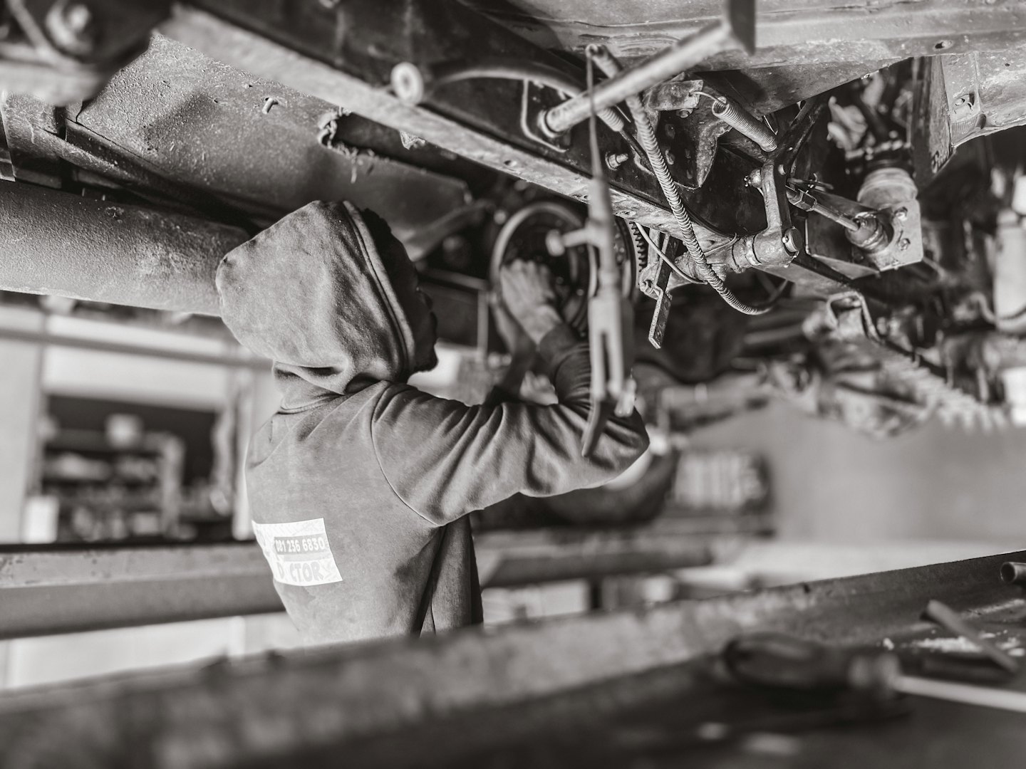 Mechanic under a car on a hoist in a repair shop.