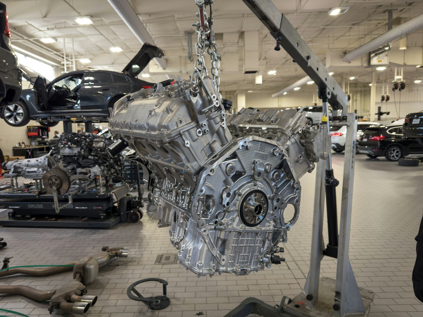 Car engine hanging from chains in a repair shop.